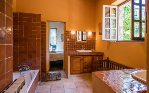 Salle de bains spacieuse aux carreaux en terre cuite, meuble vasque en bois et grande fenêtre à la villa Casa de la huerta à Millau, France