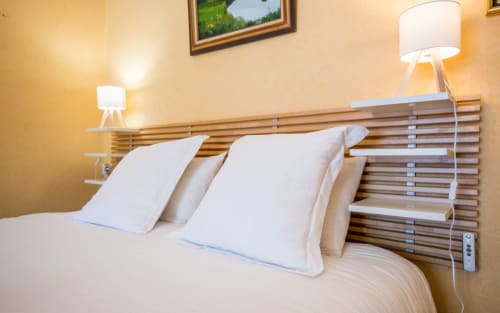 Chambre avec oreillers blancs sur le lit, tête de lit en bois et lampe de chevet, ambiance chaleureuse à la villa Casa de la huerta