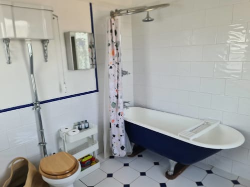 Modern bathroom at 2 Doves Holiday Property in Exeter with freestanding navy bathtub, shower, and white subway tiles