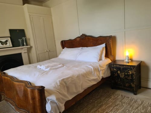 Elegant bedroom at 2 Doves Holiday Property, Exeter with wood bed frame, white linens, black nightstand and warm lighting