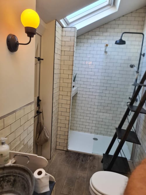 Modern bathroom at 2 Doves Holiday Property, Exeter with walk-in shower, toilet, and yellow wall sconce