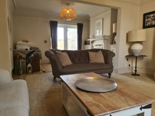 2 Doves Holiday Property Exeter: Modern lounge with brown sofa, wooden table, and natural lighting through large windows