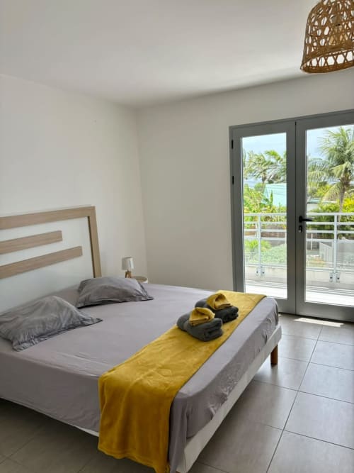 Chambre moderne avec vue mer à Maly Blue, Le Moule : lit double, balcon donnant sur les palmiers et l'océan