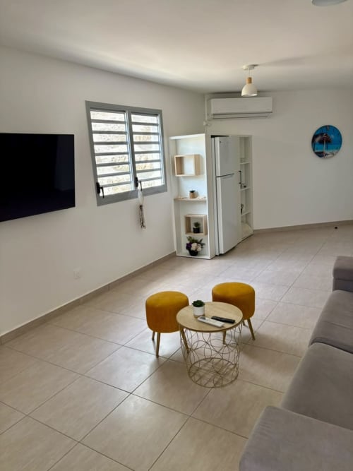 Salon moderne du duplex 2 chambres Maly Blue Location au Moule, avec canapé et vue sur mer.