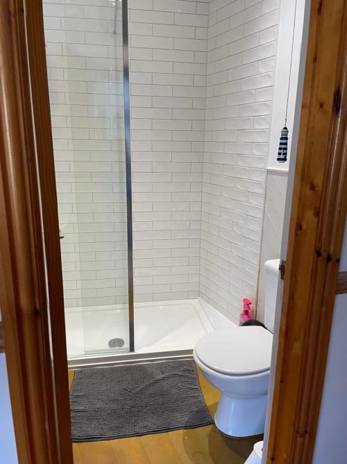 Modern bathroom with white subway tile shower, toilet, and wooden door frames at 2 Doves Holiday Property, Exeter