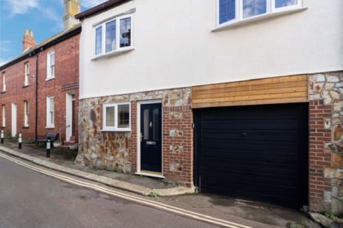 2 Doves Holiday Property exterior in Exeter with brick facade, black garage door, and stone detailing