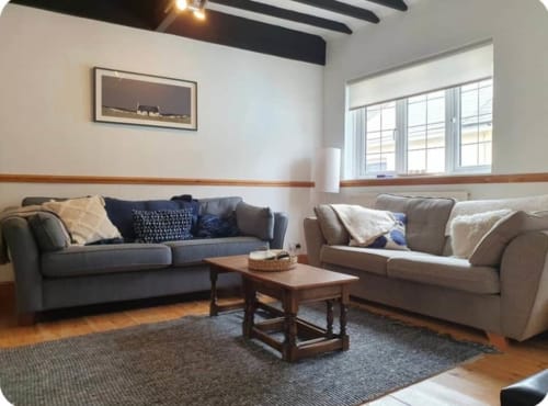 Modern living room at 2 Doves Holiday Property in Exeter with two sofas, wooden coffee table, and large windows