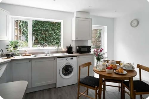 Modern kitchen-diner at 2 Doves Holiday Property, Exeter, with grey cabinetry, dining table, and garden views