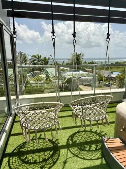 Chaises macramé suspendues sur la terrasse avec vue océan à Maly Blue, appartement au Moule Guadeloupe