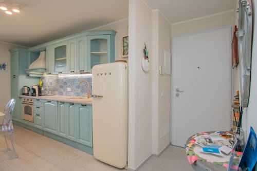 Cucina moderna con mobili turchesi, frigorifero SMEG crema e rivestimento blu mosaico all'appartamento Ancora, Varigotti