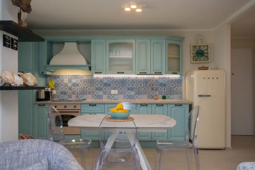 Cucina turchese con tavolo da pranzo, frigorifero color panna e rivestimento decorativo all'appartamento Ancora, Varigotti