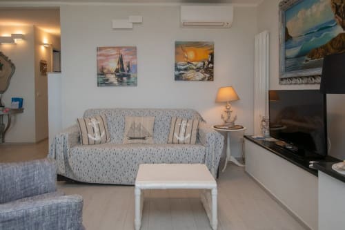 Accogliente living room dell'appartamento di Varigotti con tema nautico, dipinti di barche a vela e vista sul mare