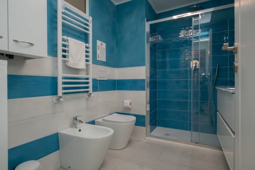 Moderno bagno con piastrelle turchese e bianche, doccia e bidet dell'appartamento Welcome Varigotti