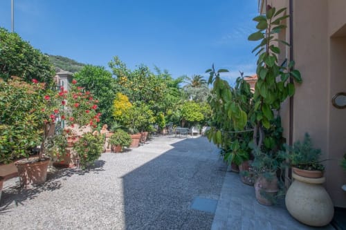 Affascinante cortile mediterraneo a Welcome Varigotti con piante fiorite, vasi in terracotta e sentieri in pietra