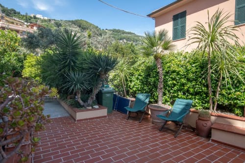 Terrazza dell'appartamento Welcome Varigotti con sdraio, palme in vaso e muri ricoperti di edera con vista sulla costa ligure