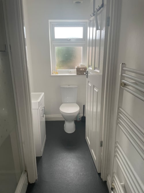 Modern bathroom with white toilet, sink, heated towel rail, and window at 2 Doves Holiday Property, Exeter