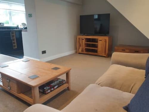Spacious living room at 2 Doves Holiday Property in Exeter with comfortable seating, wooden TV stand, and modern amenities