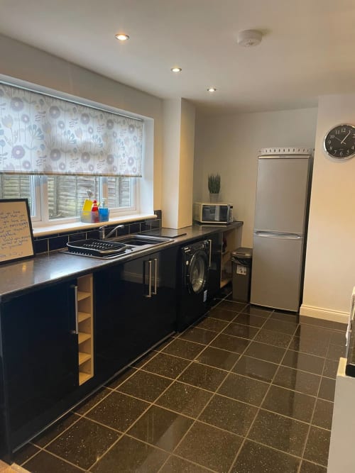 Modern kitchen at 2 Doves Holiday Property, Exeter with black cabinets, stainless steel appliances and tiled flooring