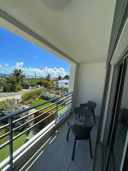 Balcon moderne de Maly Blue au Moule avec vue sur l'océan, chaises noires et jardins tropicaux