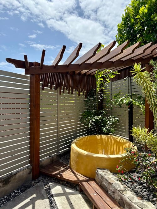 Espace spa extérieur au Maly Blue Location à Le Moule avec baignoire jaune, pergola en bois et plantes tropicales