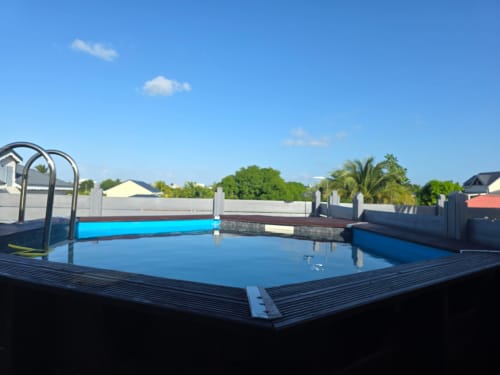 Piscine extérieure bleue de l'hôtel Maly Blue Location au Moule, Guadeloupe avec terrasse et échelle