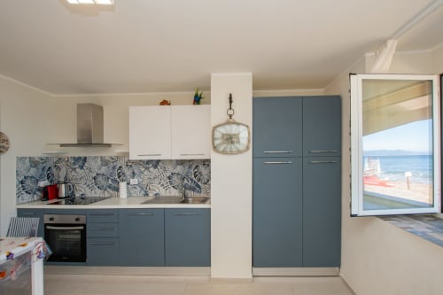 Cucina costiera moderna con mobili blu, rivestimento decorativo e vista sul mare dall'appartamento di Faro, Welcome Varigotti