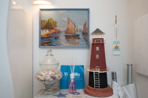 Decorazioni nautiche nell'appartamento Faro di Welcome Varigotti: modellino di faro, dipinto di barca a vela e conchiglie