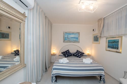Camera luminosa al Welcome Varigotti, Finale Ligure con letto a righe, quadri con vista mare e comfort moderni