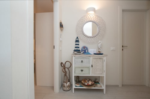 Corridoio costiero a Welcome Varigotti con mobile bianco, faro decorativo, specchio rotondo e arredi nautici