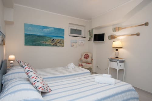 Camera da letto Faro dell'appartamento Welcome Varigotti con letti gemelli, quadro vista mare e arredamento costiero a Varigotti