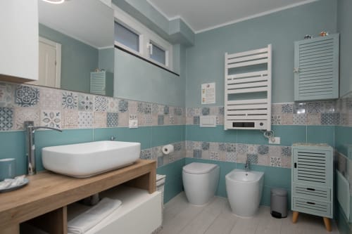 Bagno moderno dell'appartamento Welcome Varigotti a Finale Ligure, con pareti turchesi, piastrelle decorate, lavabo a bacinella e