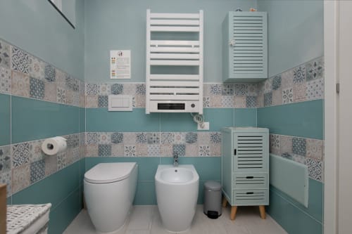 Bagno moderno nell'appartamento di Varigotti con piastrelle turchesi, accessori bianchi, scaldasalviette e armadi contenitori