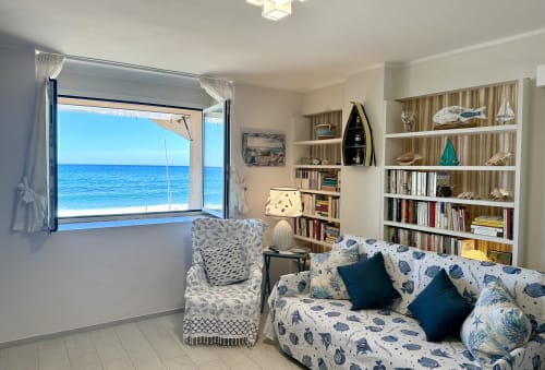 Camera da letto Faro con vista mare al Welcome Varigotti, finestra affacciata sull'oceano, divano letto con decori nautici e arredamenti integrati