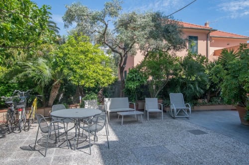 Terrazza dell'hotel Welcome Varigotti con tavolo da pranzo, sdraio, ulivi e vista sul mare a Varigotti, Italia