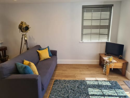 Modern living room at 2 Doves Holiday Property in Exeter with purple sofa, wooden TV stand, and nautical lamp decor