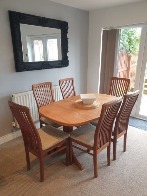 Modern dining room at 2 Doves Holiday Property with wooden table, six chairs, black framed mirror, and patio doors