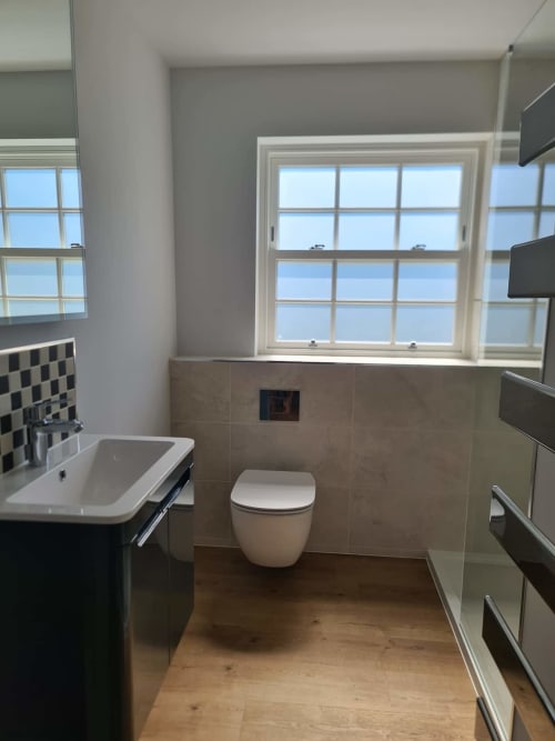 Modern bathroom at 2 Doves Holiday Property in Exeter with white toilet, sink, and large windows overlooking countryside