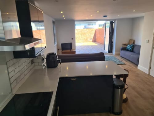 Modern open-plan kitchen and living area at 2 Doves Holiday Property, Exeter, with gray island, appliances and lounge seating