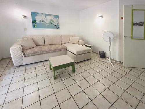 Spacieux séjour du Pavillon 44 LOCADIGNE avec canapé sectionnel beige, table basse verte et carrelage