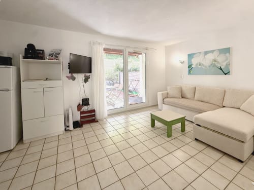 Séjour lumineux avec canapé crème, table verte, kitchenette et portes sur jardin à LOCADIGNE Digne-les-Bains