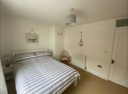 Spacious bedroom at 2 Doves Holiday Property in Exeter with striped bedding, nautical decor, and ensuite door