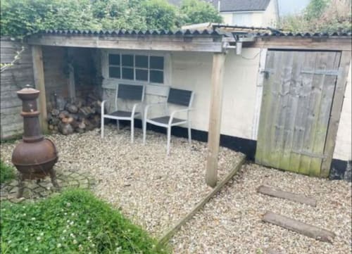 Cozy garden seating area at 2 Doves Holiday Property in Exeter with chairs, gravel patio, and chiminea.