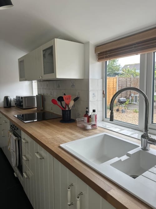 Modern kitchen with cream cabinets, wooden countertop, dual sink, and glass doors overlooking garden at 2 Doves Holiday
