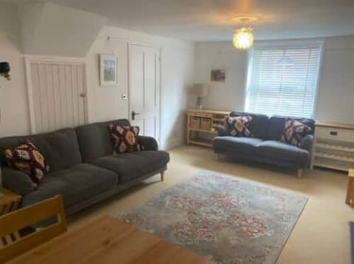 Bright living room at 2 Doves Holiday Property in Exeter with two gray sofas, patterned rug, and wooden furnishings