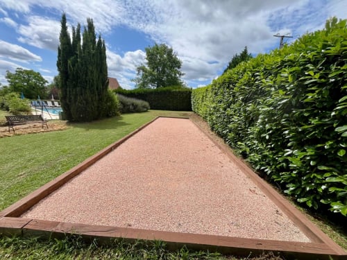 Terrain de pétanque du Gîte La Vieille Ferme de La Doinie avec haies, pelouse et piscine à Saint-Geniès