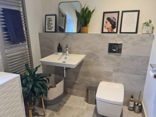 Modern bathroom at 2 Doves Holiday Property in Exeter with grey tile walls, white sink, toilet, potted plants and framed wall