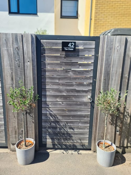 Black gate entrance to 2 Doves Holiday Property in Exeter with wooden fence panels and potted plants