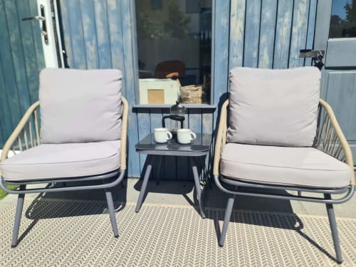 Two cushioned chairs with small table at 2 Doves Holiday Property in Exeter, outdoor seating area