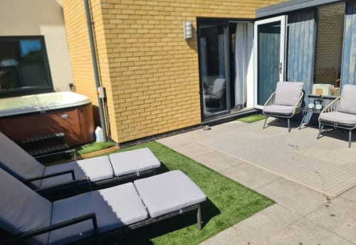 2 Doves Holiday Property patio with loungers, hot tub, and brick building in Exeter