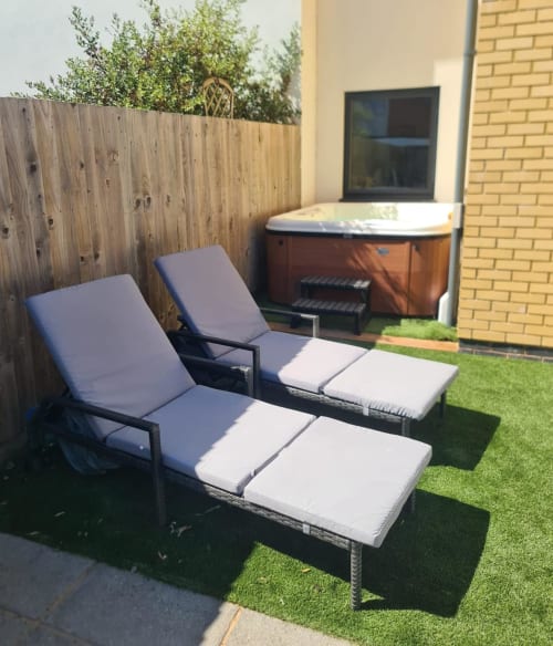 Outdoor patio seating at 2 Doves Holiday Property in Exeter with loungers, hot tub, and wooden fence
